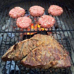 Hamburgers grilling whil roast is smoking