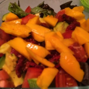 Big salad topped with mango